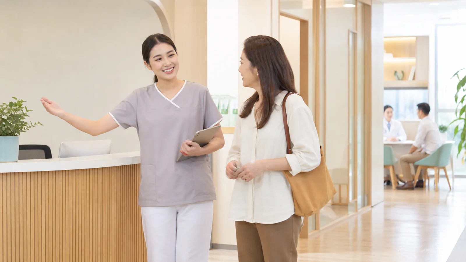 Thai clinic nurse guiding an adult patient through a bright outpatient reception area